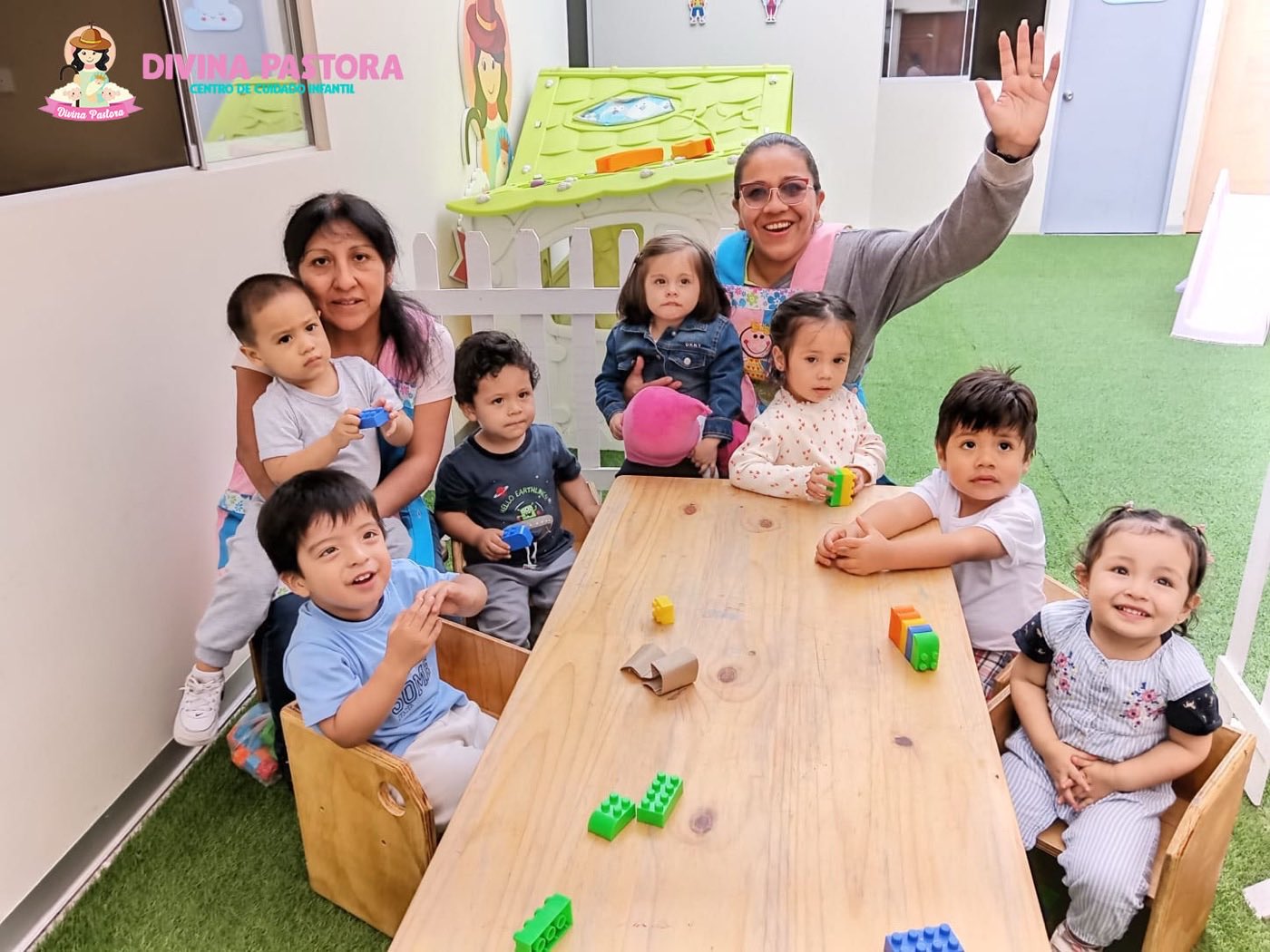 Niños jugando con bloques de construcción en una mesa de madera junto a su maestra